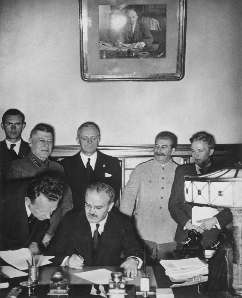 Firma del pacto. Mólotov está a punto de firmar. Tras él se encuentran Ribbentrop (con los ojos entrecerrados) y Stalin a su izquierda