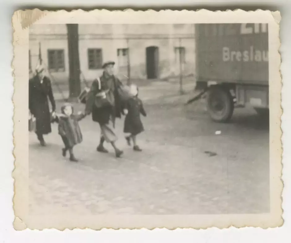 Una familia llega al punto de reunión por la Schützenstrasse. Hombres, mujeres y niños judíos de todas las edades fueron retenidos aquí durante unos días antes de ser deportados en tren. Se sabe con certeza que casi todos fueron asesinados pocos días después, en un fusilamiento documentado en Lituania. Otros fueron asesinados posteriormente en Polonia. Dos personas sobrevivieron.