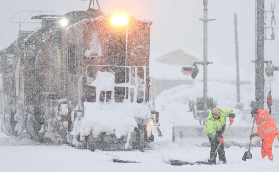 Los trabajadores limpian las vías del tren mientras cae nieve durante una poderosa tormenta invernal en Truckee, California
