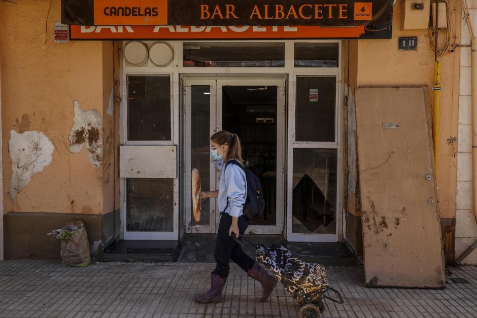 Una mujer pasa frente a la puerta de un bar de Paiporta, Valencia