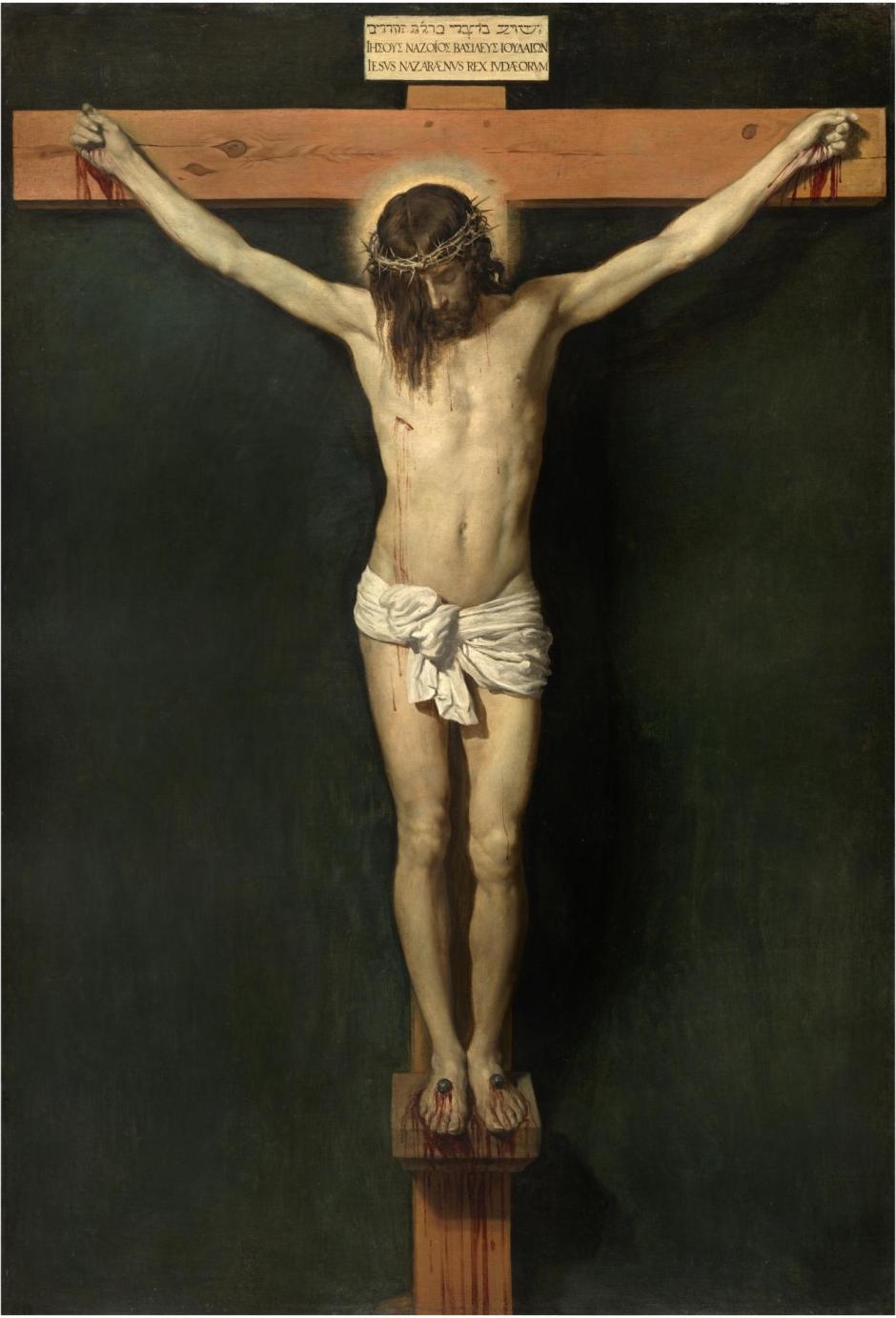 Nadie como Diego Velázquez supo reflejar el sentido teológico de Cristo en la Cruz. La serenidad del rostro de su Cristo crucificado, su divinidad y realeza, el cuerpo casi limpio de sangre y la aparente ausencia de sufrimiento contribuyen a una representación más mística que física de la muerte de Jesús en el Calvario.
Su pintura está desprovista de violencia. Salvo la herida del costado y los calvos en manos y pies, no hay heridas. ¿Está negando Velázquez que Cristo haya sufrido en la Cruz por el perdón de los pecados en una suerte de herejía? En absoluto.
Velázquez no retrata el sufrimiento de Cristo porque está mostrando a un Cristo victorioso sobre la muerte y el pecado. Retrata a ese Cristo mesiánico que, en la Cruz, ha dado cumplimiento a las profecías bíblicas al alzarse como redentor de la humanidad desde su trono del madero.