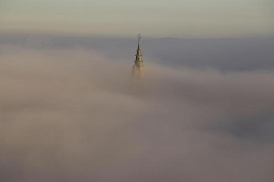 TOLEDO, 25/01/2024.- La niebla que cubre por completo el casco histórico de Toledo, a primera hora de la mañana, empieza a dejar ver el campanario de la catedral primada y el Alcázar de la ciudad. EFE/Ismael Herrero
