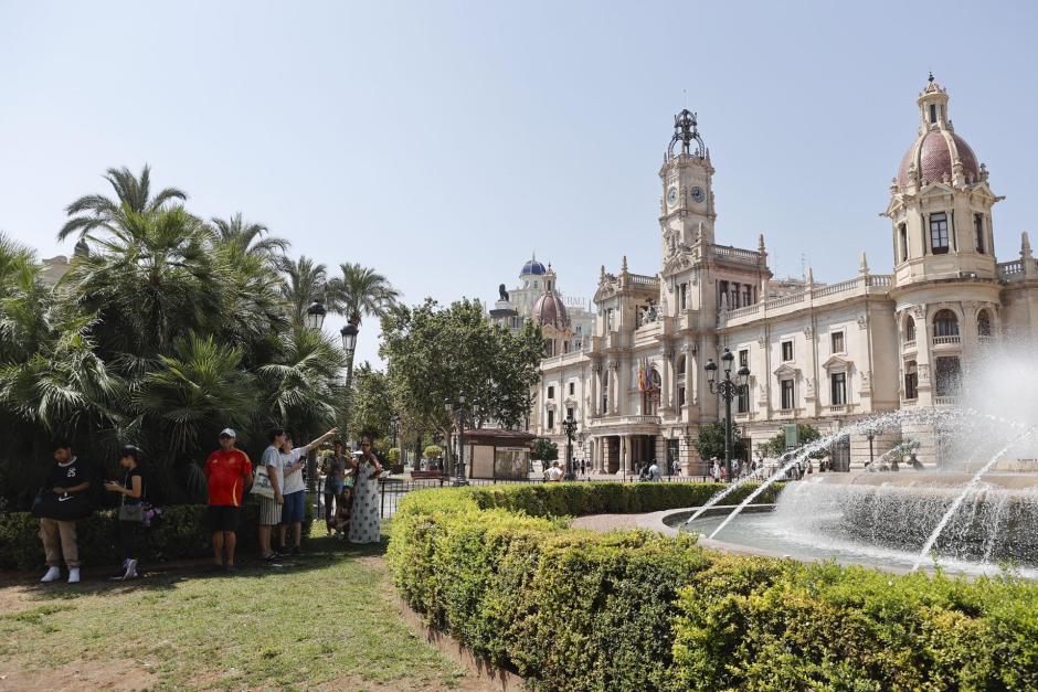 Imagen tomada este viernes de varios turistas a la sombra junto a la fuente de la plaza del Ayuntamiento de Valencia