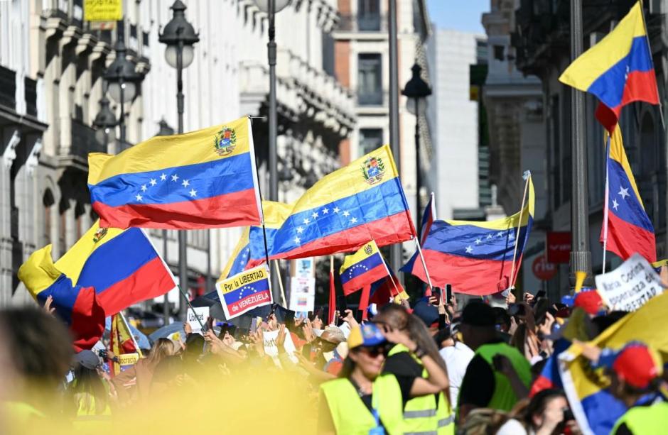 Supporters of Maria Corina Machado holding Venezuelan flags gather while waiting for the Venezuelan opposition leader in Madrid's Puerta del Sol on April 18, 2026. (Photo by Javier SORIANO / AFP)