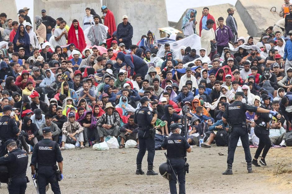 FOTODELDIA CEUTA, 21/08/2026.- La policía vigila a inmigrantes que continúan viviendo en las inmediaciones de la playa del Trampolín en Ceuta, este viernes. El secretario de Estado Juventud e Infancia, Rubén Pérez Correa, ha considerado "factible" llevar a cabo "en un plazo de pocas semanas" el traslado de 500 niñas migrantes no acompañadas desde Ceuta a la Península y, para ello, confía en la "voluntad" del Gobierno de la ciudad autónoma. EFE/Reduan