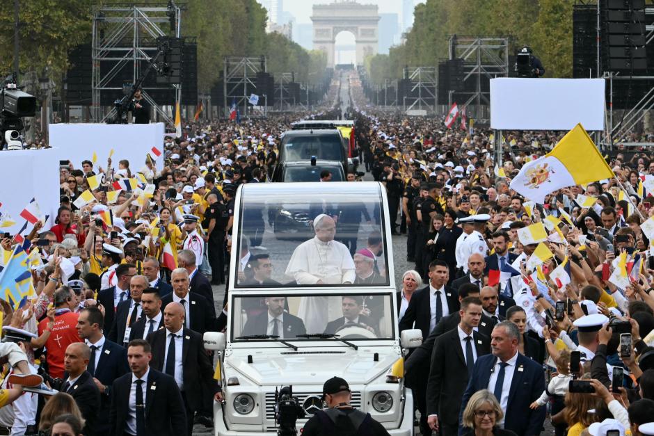 León XIV saluda a la multitud desde el «Papamóvil» mientras recorre la avenida de los Campos Elíseos, con el Arco del Triunfo al fondo, de camino a la plaza de la Concordia, en el centro de París