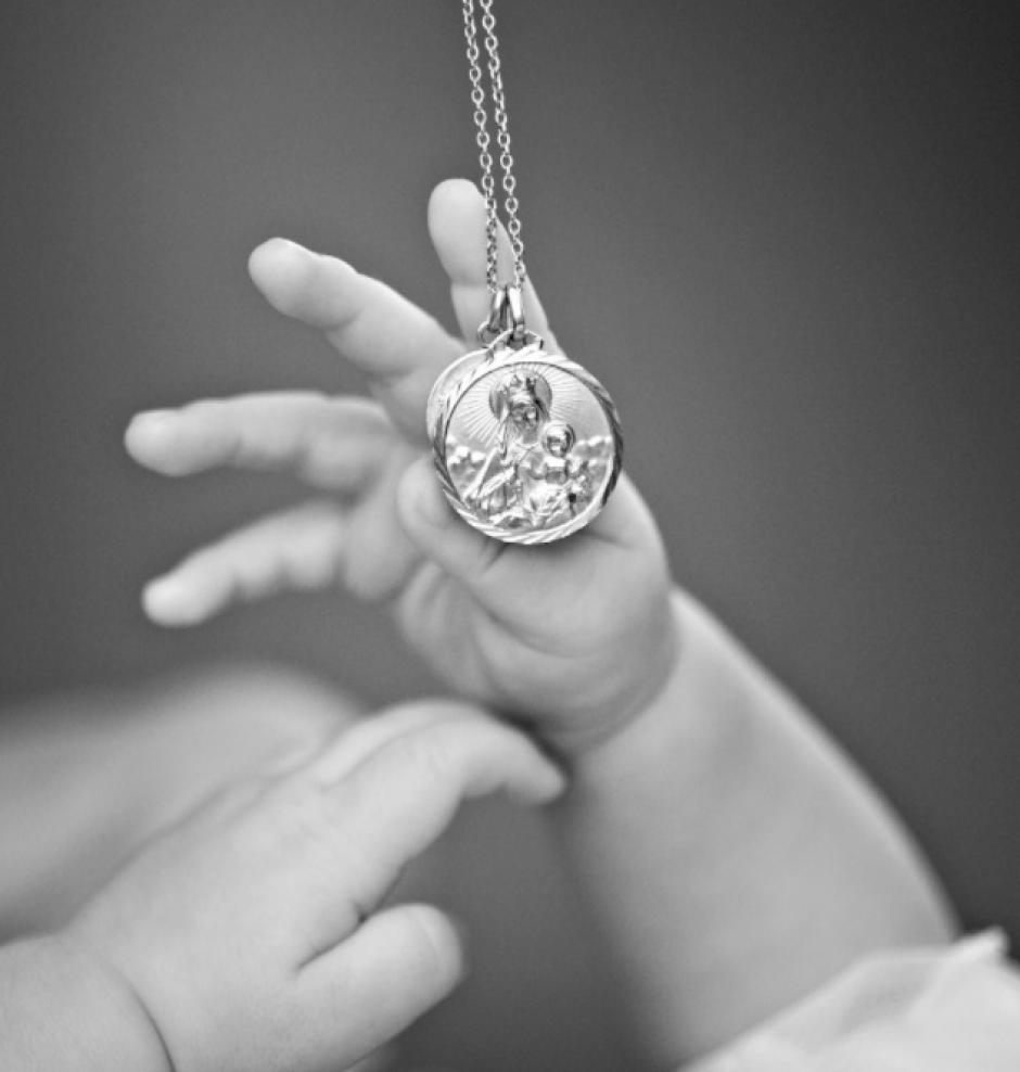Un bebé con la medalla propia que los padrinos regalan en el bautizo