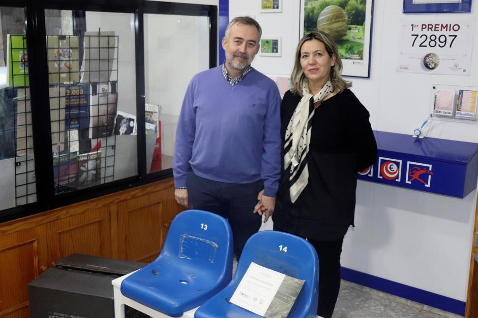 Óscar y Paloma, que regentan una administración de lotería en Cáceres, posan junto a dos asientos del antiguo Vicente Calderón en memoria de su hijo Pablo