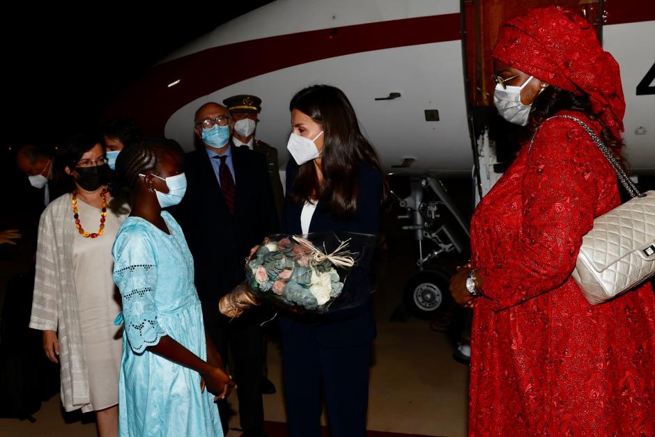 Doña Letizia, recibida por Marème Faye Sall, primera dama de la República de Senegal y una niña que le entrega presentes.