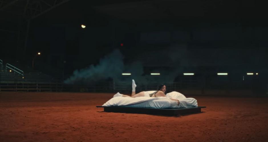 Rosalía en una cama situada en una pista hípica, en el videoclip de 'Hentai'