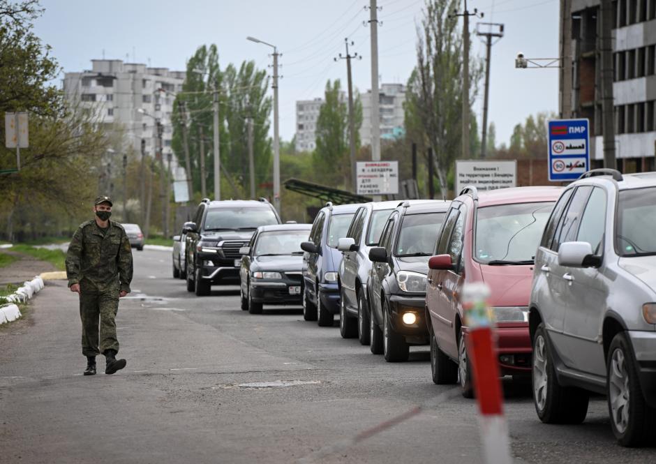 Un militar de Transnistria pasa junto a coches que hacen cola para salir de Transnistria hacia Moldavia, el 28 de abril