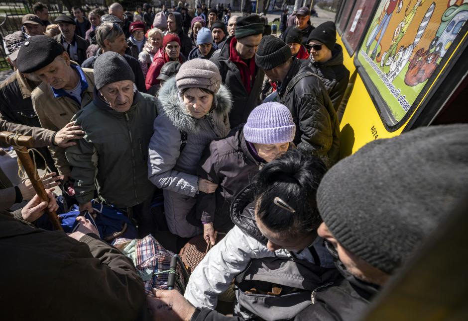 La muchedumbre se aglutina frente a la entrada de un bus en las primeras y únicas evacuaciones.