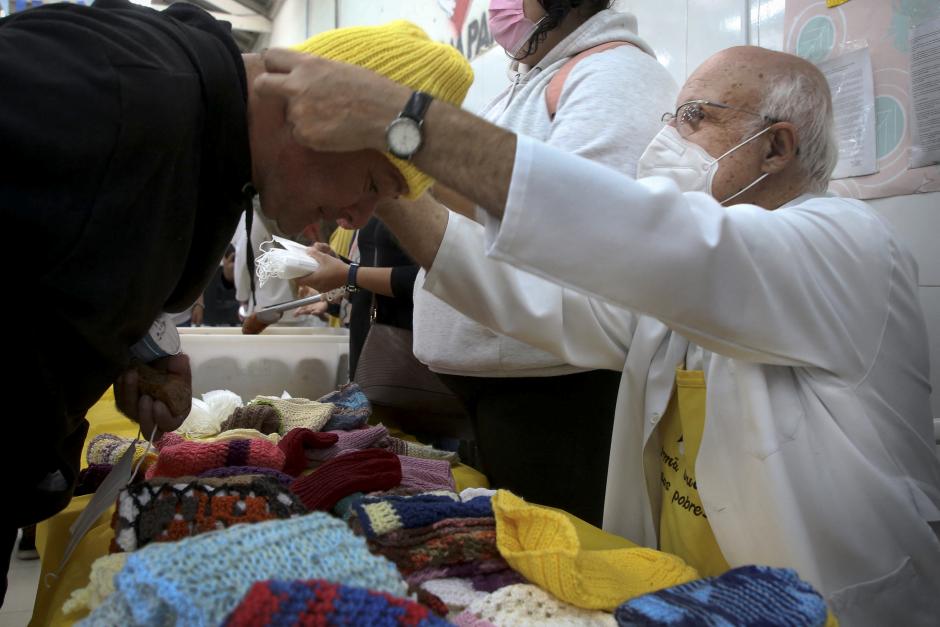 El sacerdote católico repartiendo ropa entre los sintecho del centro comunitario