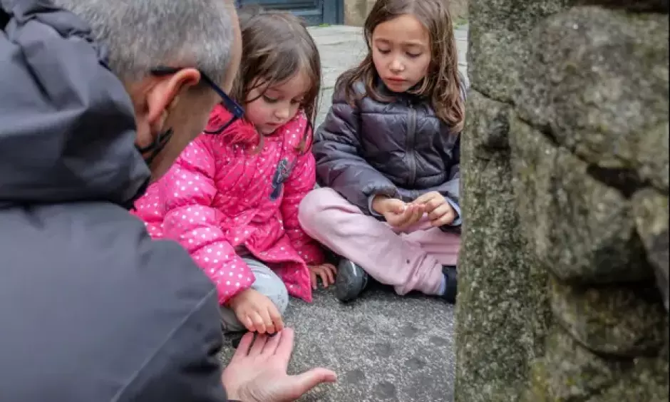 Dos niñas aprenden a jugar a las 'tres en raya' en las hendiduras de piedra de Santiago de Compostela