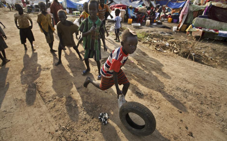Displaced children play games with an old tyre at a United Nations compound which has become home to thousands of people displaced by the recent fighting, in the capital Juba, South Sudan Sunday, Dec. 29, 2013.