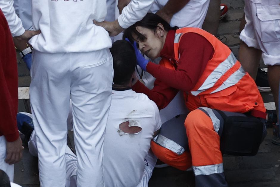 Los servicios de Cruz Roja atienden a un herido por magulladuras tras el segundo encierro de los Sanfermines 2022.