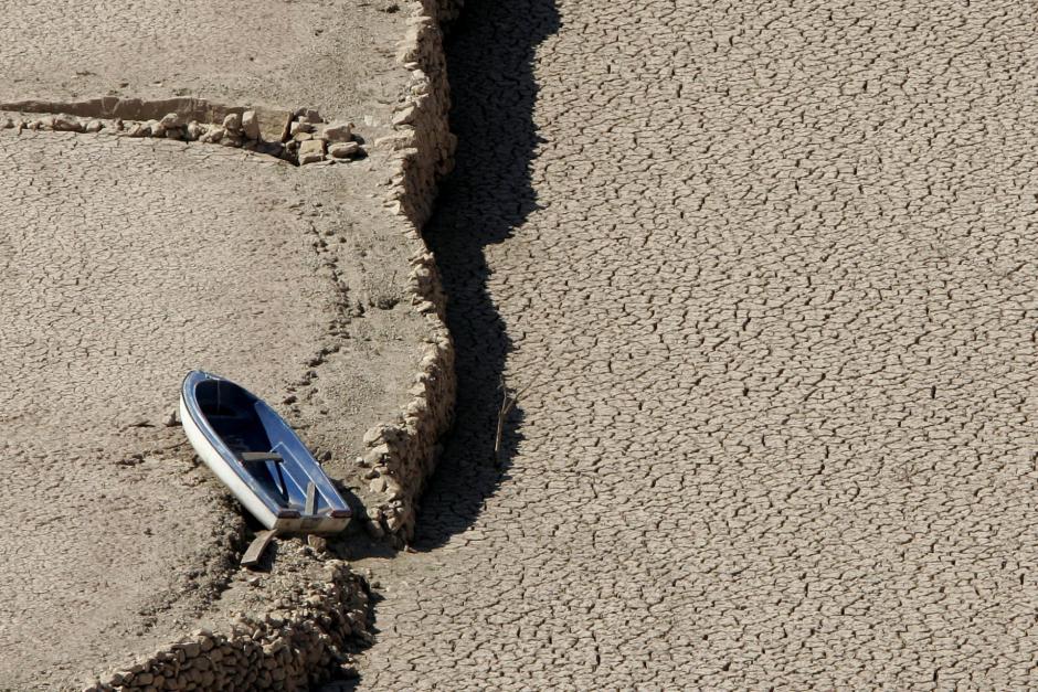 A small boat sits in the dried bottom of the Arenos reservoir near Pueblo de Arenos, eastern Spain,  Friday Aug. 5, 2005. Spain is experiencing its driest summer since record-keeping began in the 1940s. (AP Photo/ Fernando Bustamante) **EFE OUT**