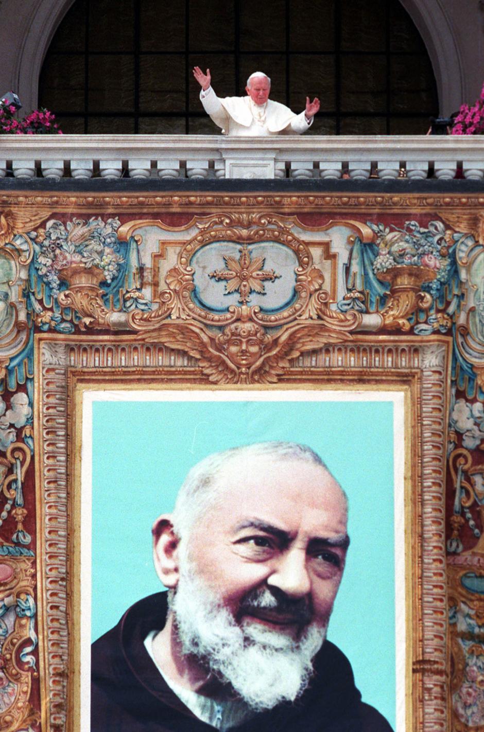 FILE - In this May 2, 1999 file photo, Pope John Paul II acknowledges the faithful above the tapestry of Italy's most famous Capuchin monk Padre Pio, hung on St. John in Lateran Basilica in Rome during his beatification ceremony.