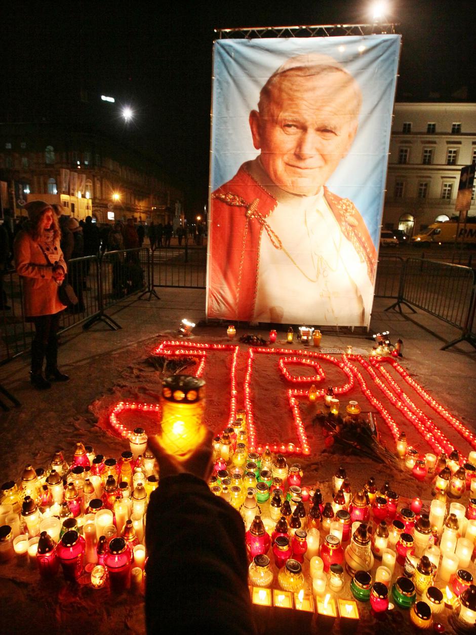 People pray near a large poster of the late Pope John Paul II as they gather in Pilsudski Square in Warsaw, Poland, Thursday, April 2, 2015, for prayers and a vigil that will mark the 10th anniversary of his death.