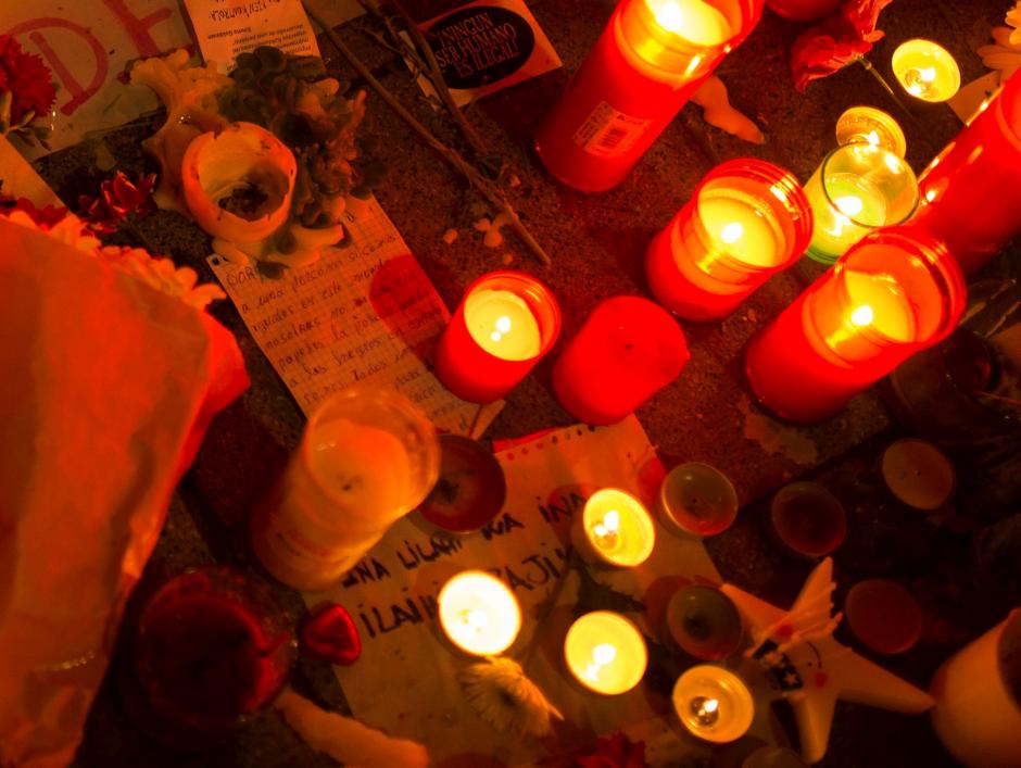 A photograph of Senegalese Mame Mbaye rests among lighted candles placed by people at the end of a protest after the death of Mbaye at the Lavapies neighborhood in Madrid, Friday, March 16, 2018.  Sheets read in Spanish: "Mmame Mbage killed by the police," "Mame Mbaye is alive."