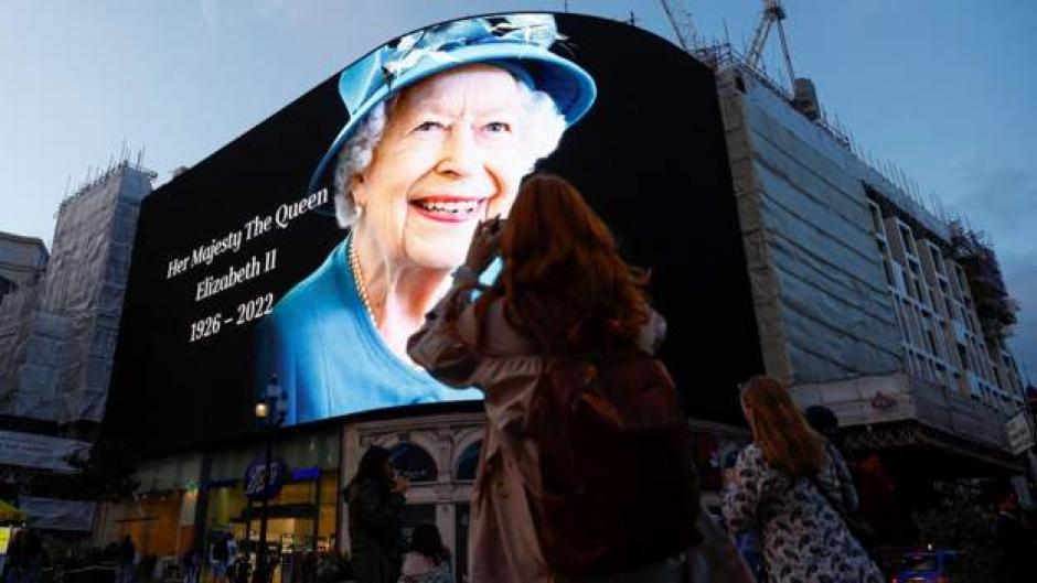 En Piccadilly Circus, en el centro de Londres, la gente toma fotografías de una gran imagen que marca la muerte de la reina Isabel II