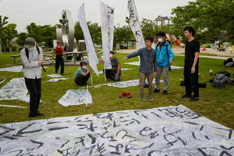 This photo taken on May 20, 2022 shows French visual artist and dancer Eric Minh Cuong Castaing (R) at a park preparing banners to be used in a demonstration staged by former "hikikomori", or shut-ins, and their friends in Takatsuki, Osaka prefecture. - Through an experimental theatre project, two French artists are hoping to offer Japan's socially isolated hikikomori who are recovering a chance to express themselves and regain self-confidence. (Photo by Kazuhiro NOGI / AFP) / TO GO WITH Japan-France-culture-theatre-hikikomori,FEATURE by Etienne BALMER