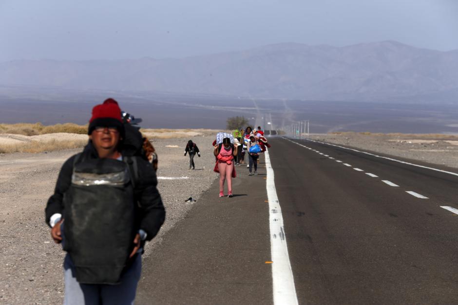 Inmigrantes, en su mayoría venezolanos, caminan por el arcén de una carretera después de cruzar a Chile desde la frontera con Bolivia, cerca de Colchane, Chile, el sábado 6 de febrero de 2021