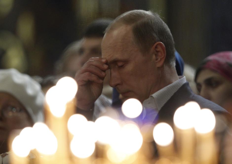 Russia's President Vladimir Putin, center, crosses himself as he attending the Orthodox Christmas service in Sochi, Monday,  Jan. 6, 2014.