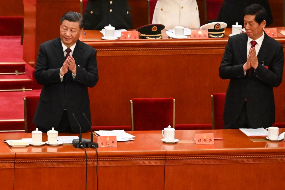 El presidente de China, Xi Jinping (izquierda), aplaude con el miembro del Comité Permanente del Politburó, Li Zhanshu, mientras se paran a cada lado del asiento vacío del expresidente Hu Jintao durante la ceremonia de clausura del XX Congreso del Partido Comunista Chino