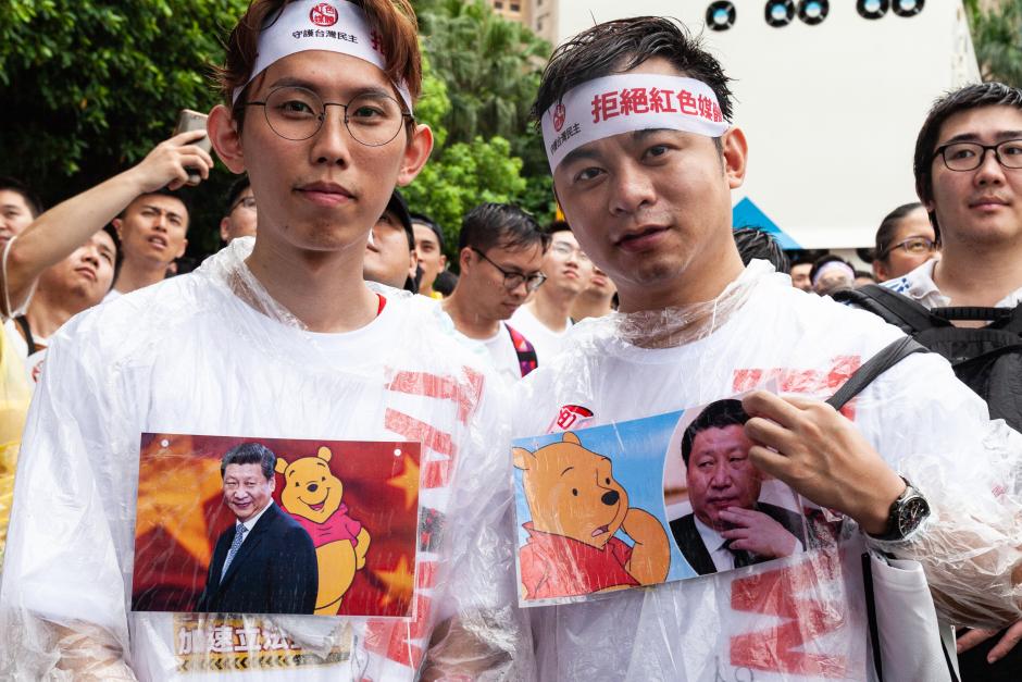Manifestantes de pie bajo la fuerte lluvia con camisetas que representan al presidente de la República Popular China, el presidente Xi Jinping, junto con Winnie the Pooh, en Taipei, Taiwán