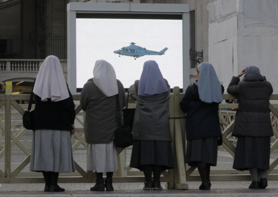 Nuns watch a giant screen showing  a helicopter with Pope Benedict XVI onboard in St. Peter's Square, at the Vatican,Thursday, Feb. 28, 2013.