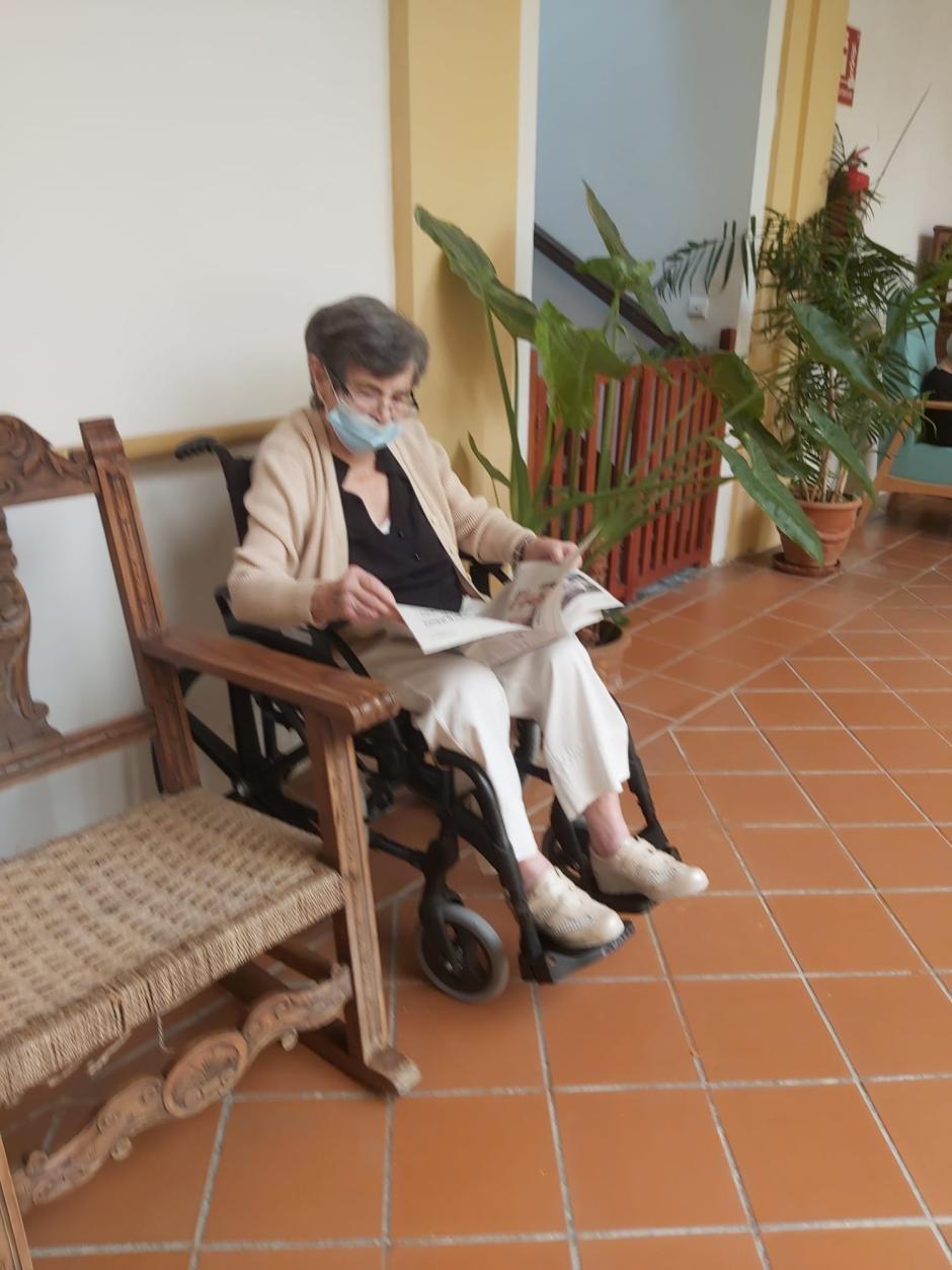 Carmen Valls lee el periódico en el patio de la residencia