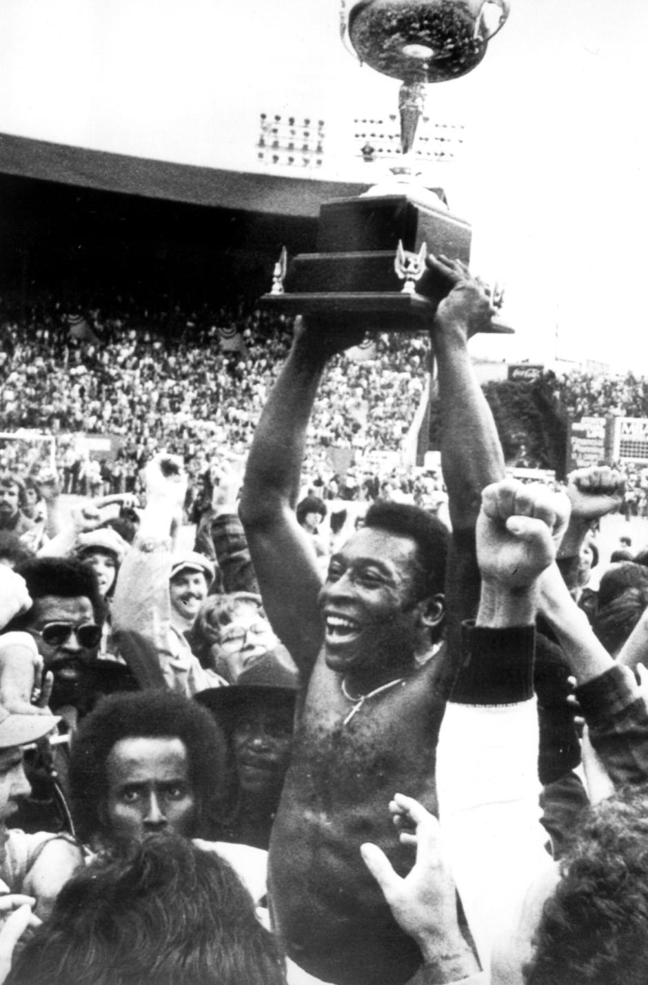 Pelé, sosteniendo el trofeo de campeón de los EE. UU. conquistado sobre su cabeza, rodeado de fanáticos que lo vitoreaban el 29 de agosto de 1977 en el Estadio de Portland (Estado de Oregón)