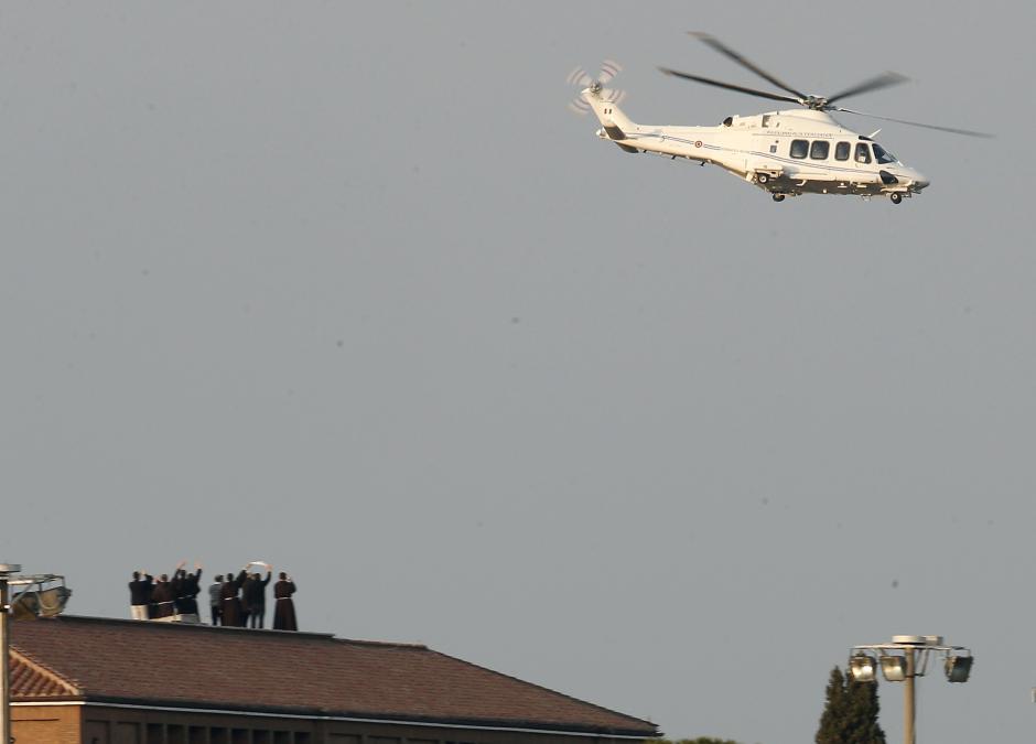 Monks on a roof wave as the helicopter with Pope Benedict XVI onboard leaves the Vatican in Rome, Thursday, Feb. 28, 2013.