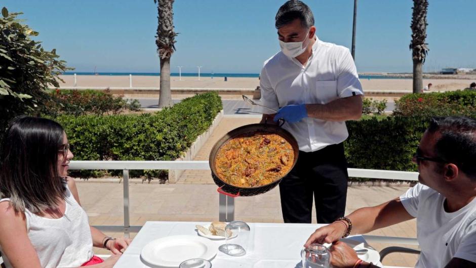Un camarero enseña una paella en la valenciana playa de La Malvarrosa