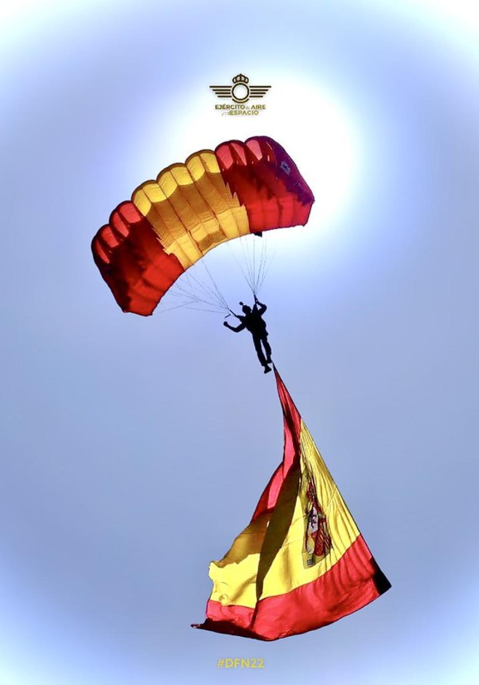 Un miembro de la Patrulla Acrobática de Paracaidismo salta con la bandera de España