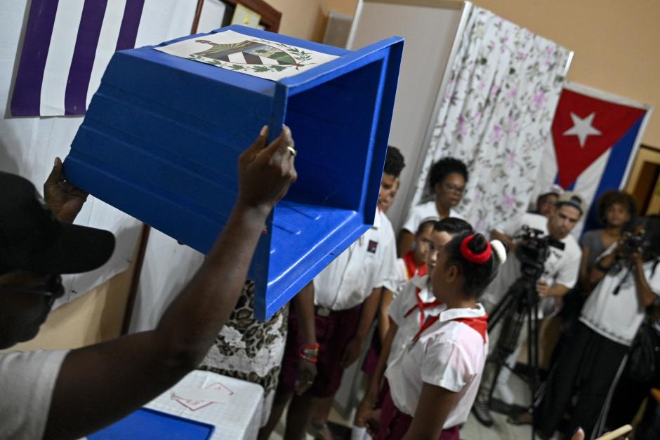An authority (L) shows an empty ballot box before balloting begins at a polling station in Havana, on March 26, 2023, during the country's legislative election. - Cubans vote on Sunday to renew the parliament for five years with 470 candidates for deputies to fill the same number of seats and with abstentionism as the only enemy to be defeated. (Photo by ADALBERTO ROQUE / AFP)