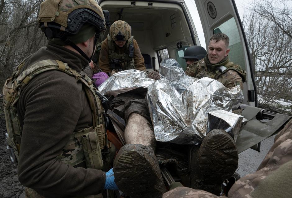 Medics from the Da Vinci Wolves Battalion evacuate a wounded Ukrainian serviceman near the front line of Bakhmut, Donetsk region, on April 1, 2023, amid the Russian invasion of Ukraine. - Churned-up roads have been turned into quagmires by melted snow, making the journey slow. The ambulance is coated in mud from wheels to roof. (Photo by Genya SAVILOV / AFP)