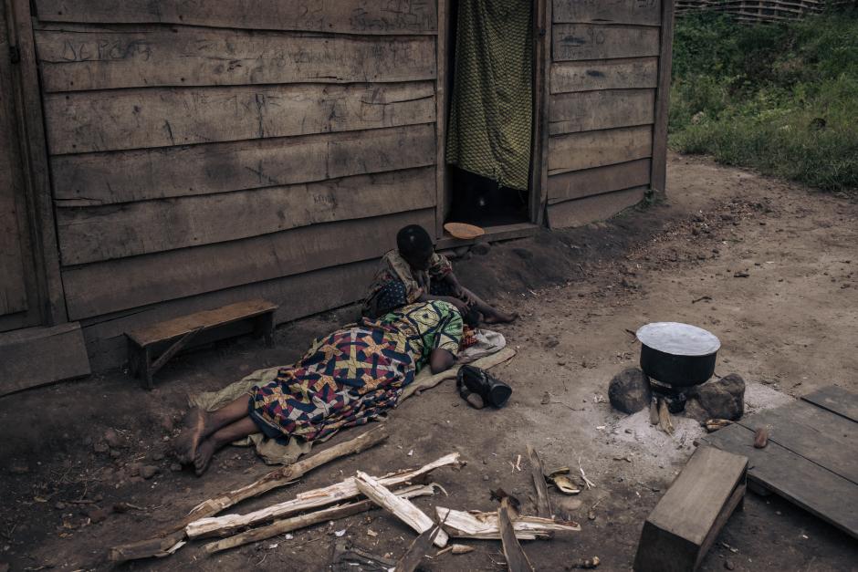 A girl and a woman rest in front of their house in Kishishe, eastern Democratic Republic of Congo, on April 5, 2023. - In late November 2022, according to UN reports, M23 (March 23 Movement) fighters massacred at least 170 civilians in Kishishe in a retaliation attack after being ambushed by a local armed group. For a year, the fighters of the M23 - "Movement of March 23", a predominantly Tutsi armed group - have been advancing in Congolese territory, taking control of main roads, seizing towns and border posts. The capture of Kishishe is also part of a fight by the M23 against the FDLR (Democratic Forces for the Liberation of Rwanda), a mainly Hutu armed group founded by former leaders of the genocide in Rwanda, exiled in the DRC. The latter have for years installed one of their bastions in the immediate vicinity of the village. (Photo by ALEXIS HUGUET / AFP)