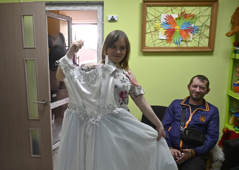 Vitaly Sorokin, de 48 años, sonriendo mientras su esposa Veronika, de 23, muestra su vestido de novia en la capital ucraniana de Kiev