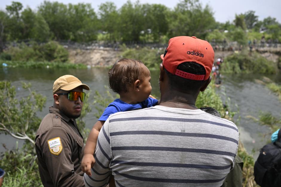 Migrants are given water by a member of the US military after they crossed into the United States from Mexico, in Brownsville, Texas, on May 11, 2023. - The US on May 11, 2023, will officially end its 40-month Covid-19 emergency, also discarding the Title 42 law, a tool that has been used to prevent millions of migrants from entering the country. (Photo by Andrew CABALLERO-REYNOLDS / AFP)