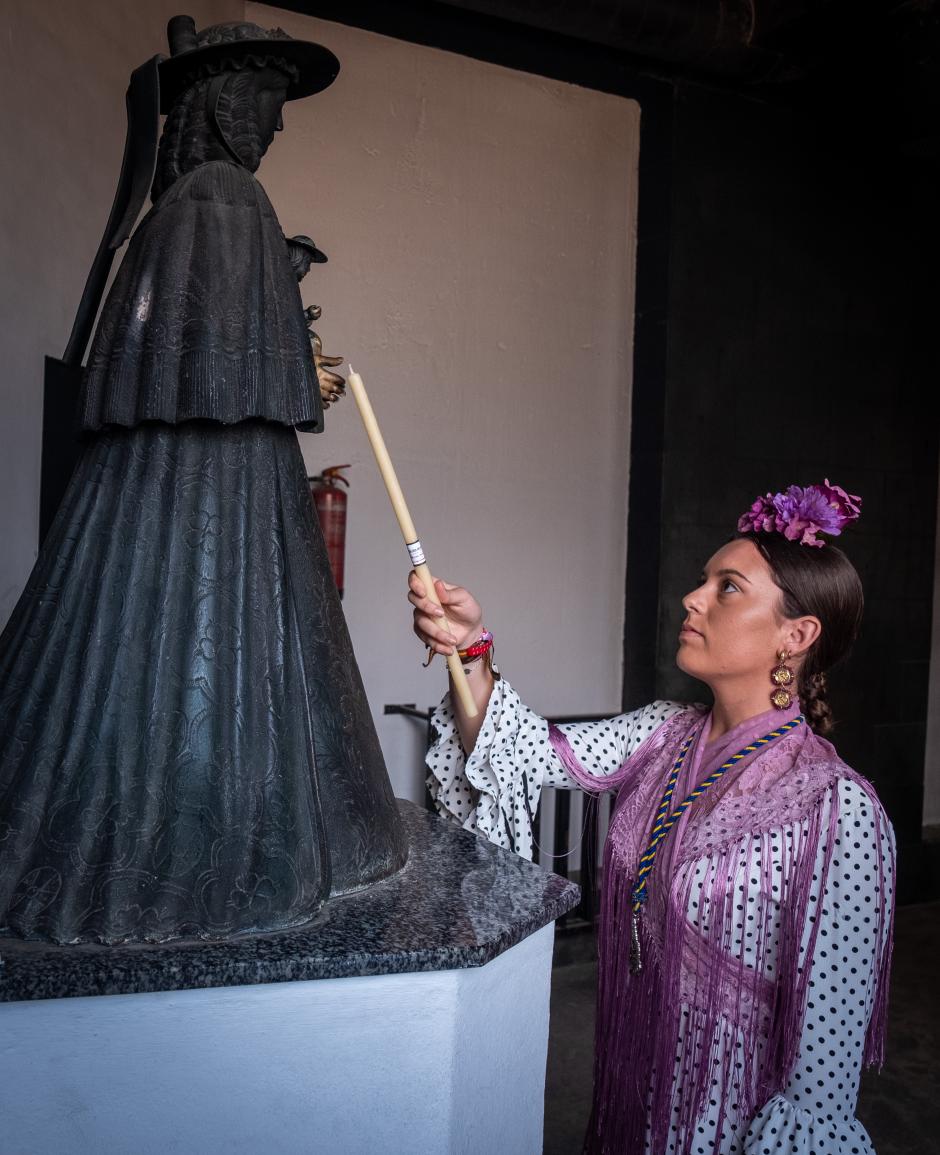 EL ROCÍO (HUELVA), 28/05/2023.- Una mujer enciende una vela este domingo en el velario del Santuario de la Virgen del Rocío de la aldea almonteña de El Rocío (Huelva). EFE/Julián Pérez