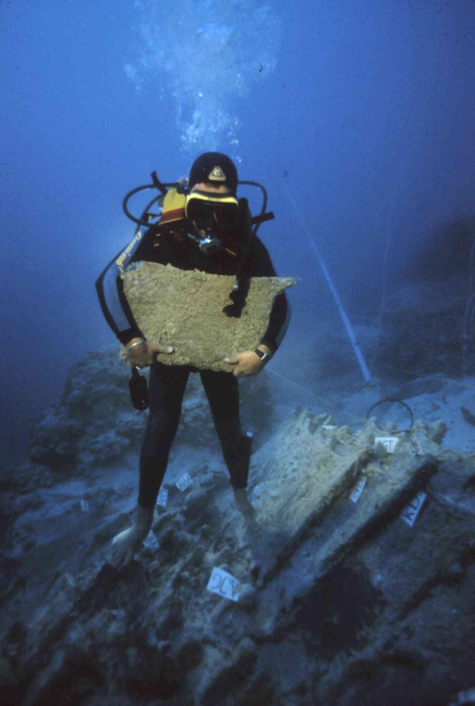 Un arqueólogo submarino recogiendo un lingote