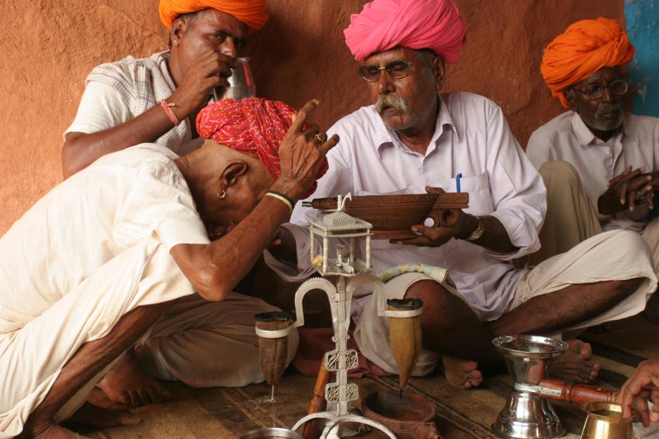 Un anciano hace el símbolo de los cuernos de la vaca en el momento de beber una infusión de opio, Rajasatán, India