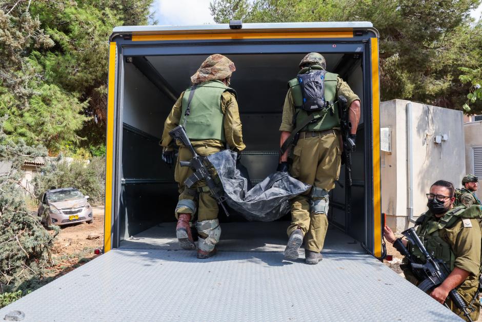 Israeli soldiers remove the body of a compatriot, killed during an attack by the Palestinian militants, in Kfar Aza, south of Israel bordering Gaza Strip, on October 10, 2023. Israel pounded Hamas targets in Gaza on October 10 and said the bodies of 1,500 Islamist militants were found in southern towns recaptured by the army in gruelling battles near the Palestinian enclave. (Photo by JACK GUEZ / AFP)