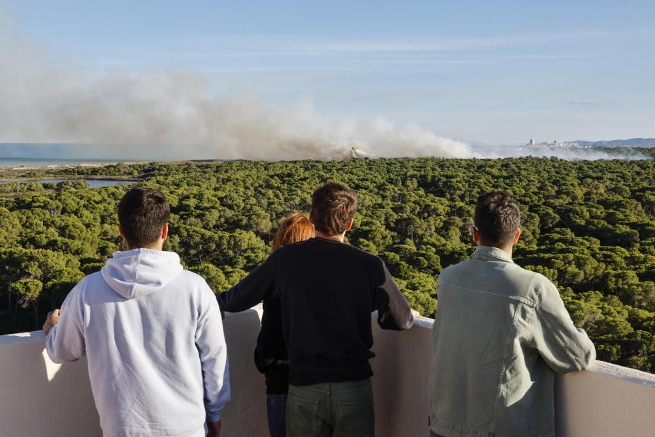 Varias personas contemplan las labores de extinción del último incendio en El Saler, Valencia