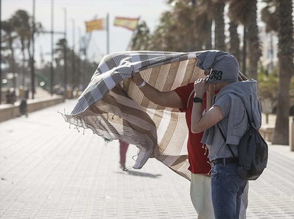 Dos personas se refugian del viento en el paseo de la playa de la Malvarrosa en Valencia de las rachas de viento del temporal Ciarán