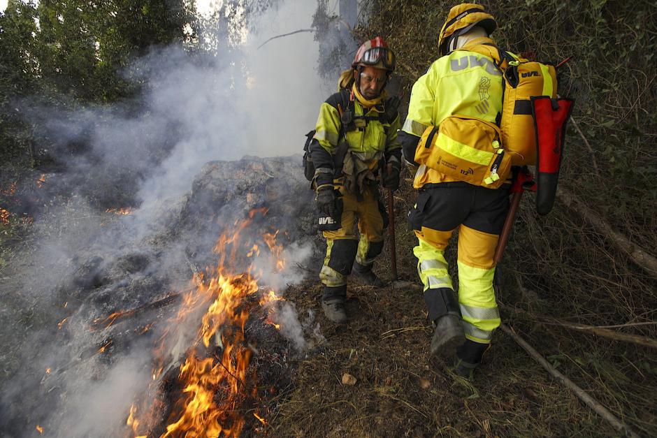 Dos bomberos trabajan junto a las llamas del incendio de Montichelvo, en el municipio valenciano de Ador