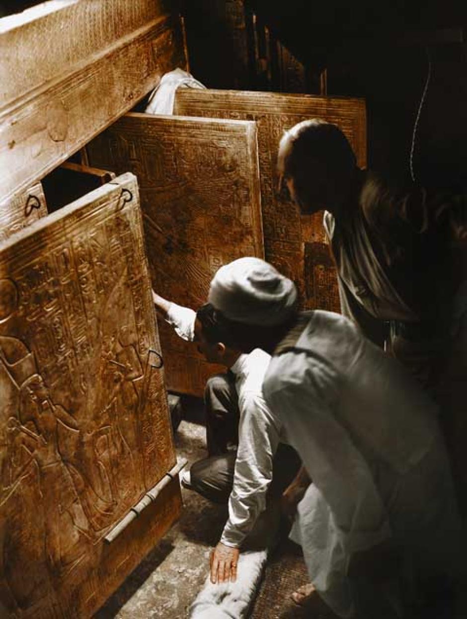 Howard Carter (arrodillado), Arthur Callender y un obrero egipcio en la Cámara Sepulcral, mirando a través de las puertas abiertas de los cuatro santuarios dorados hacia el sarcófago de cuarcita