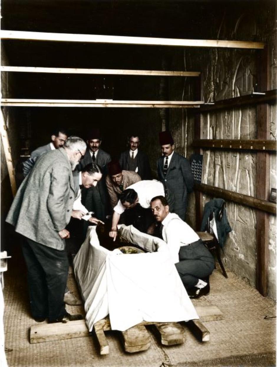 El comité de Examen de Tutankamón observa cómo el Dr. Douglas Derry realiza la primera incisión en el envoltorio que cubre el cuerpo momificado de Tutankamón. Derry es asistido por su colega el Dr. Saleh Bey Hamdi (a su derecha), mientras Pierre Lacau (izquierda), Howard Carter (segundo a la izquierda) y otros observan.